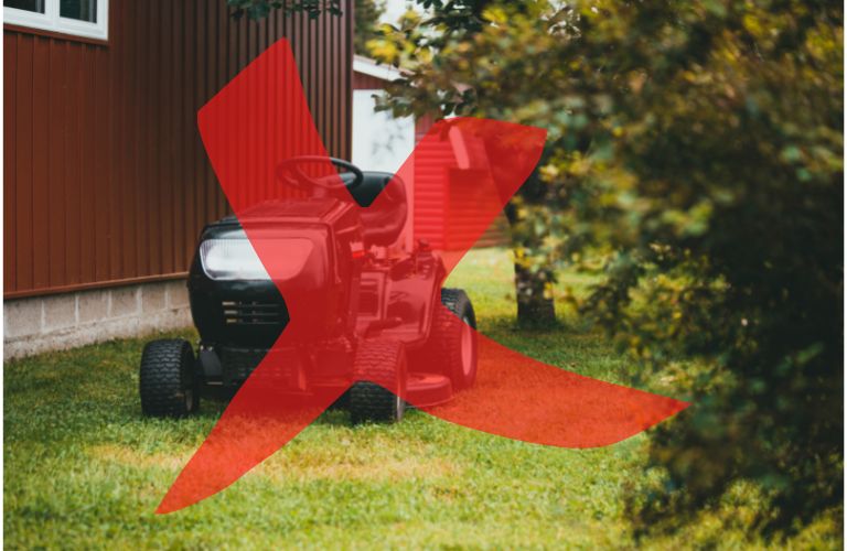 riding lawnmower parked by a shed or house on the grass with a partially transparent letter X in red crossing the mower out