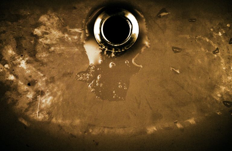 dark bronze sink with water draining down it