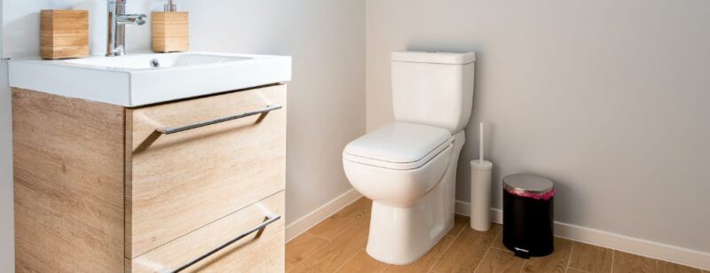 Clean white toilet in white bathroom with countertop