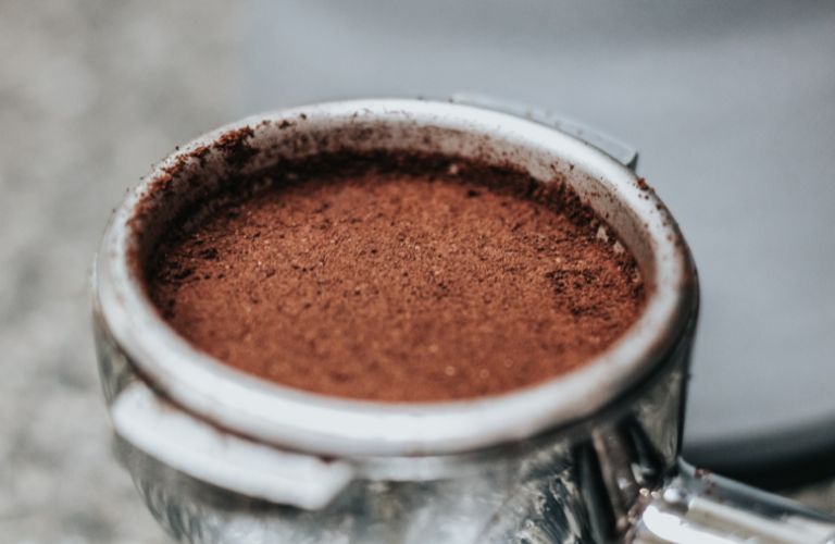 spoon of coffee grounds close up in a metal measuring spoon