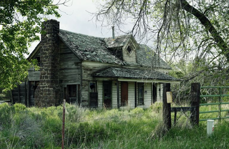 old abandoned or condemned house with stone chimney and broken shingles