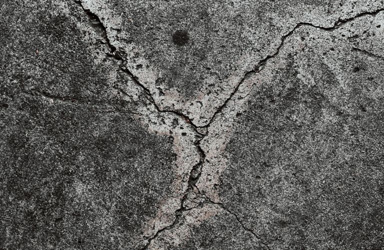 cracked concrete with dark spots and light spots close up texture