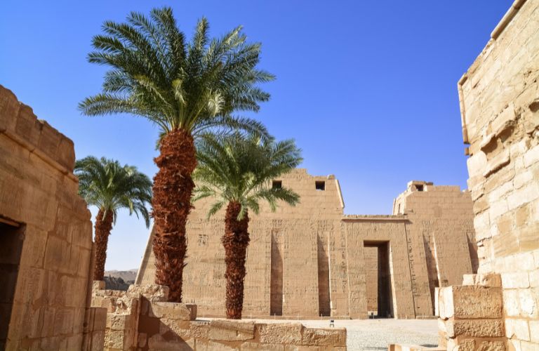 Ancient Egyptian ruins with trees and blue sky