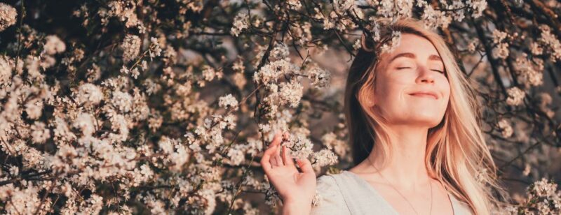 woman smelling flowers blooming on a tree