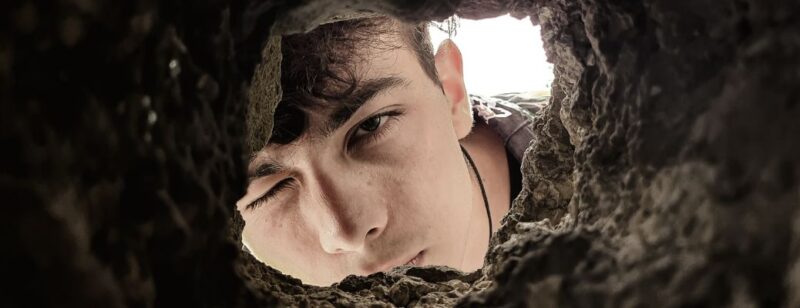 young man looking into hole dug in dirt