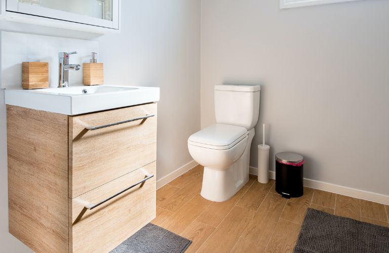 toilet in a clean bathroom with a wood drawer sink and wood floor