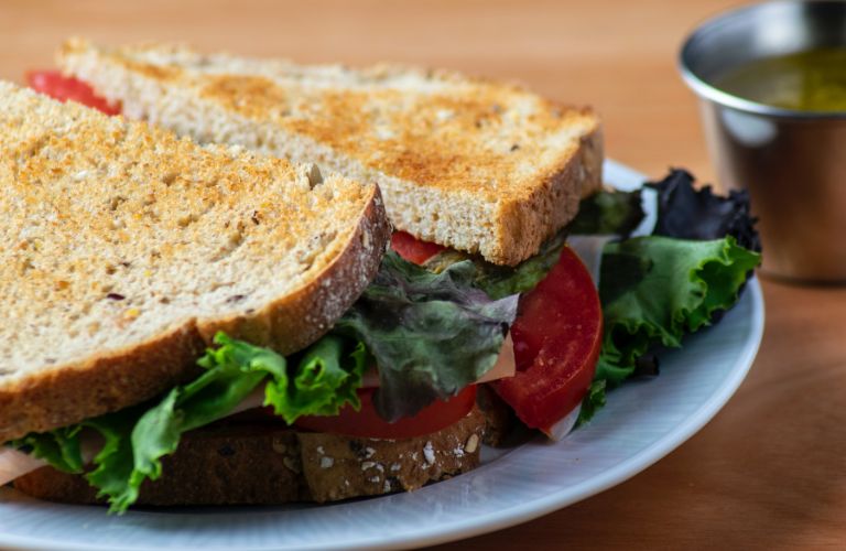 toasted bread turkey sandwich with lettuce cheese and tomatoes on a plate