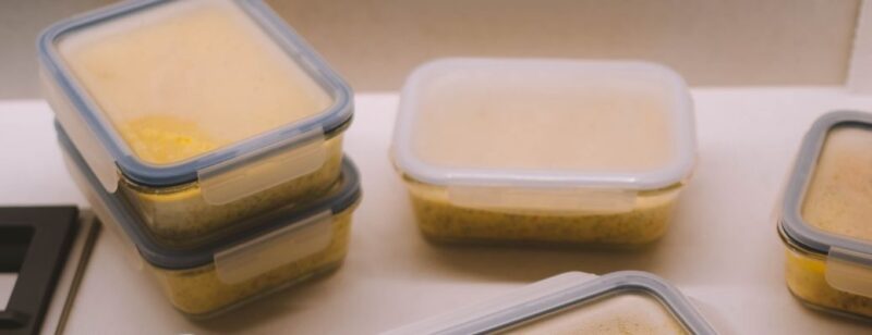 food containers of clear plastic with food inside lids undone sitting on a countertop or in a fridge