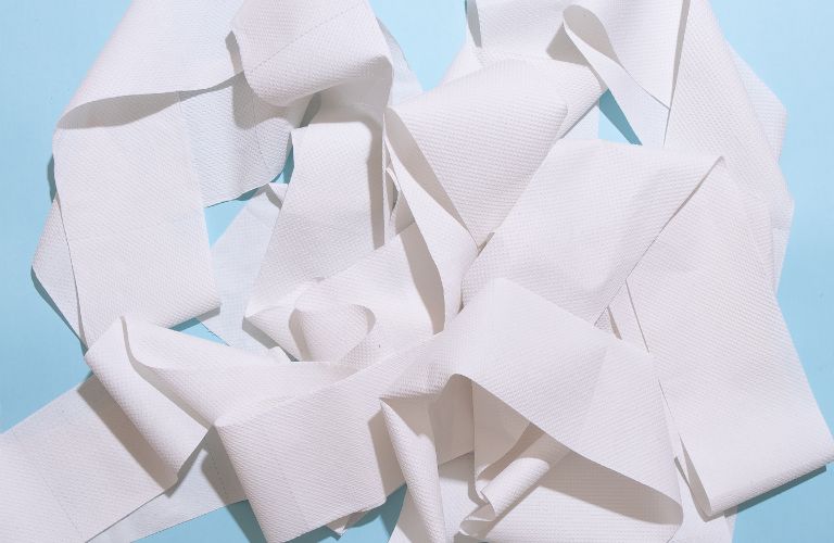 toilet paper unrolled lying on top of itself in a pile on a blue surface