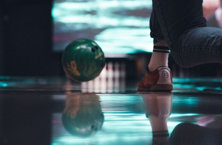 person throwing a bowling ball down a lane in neon lights