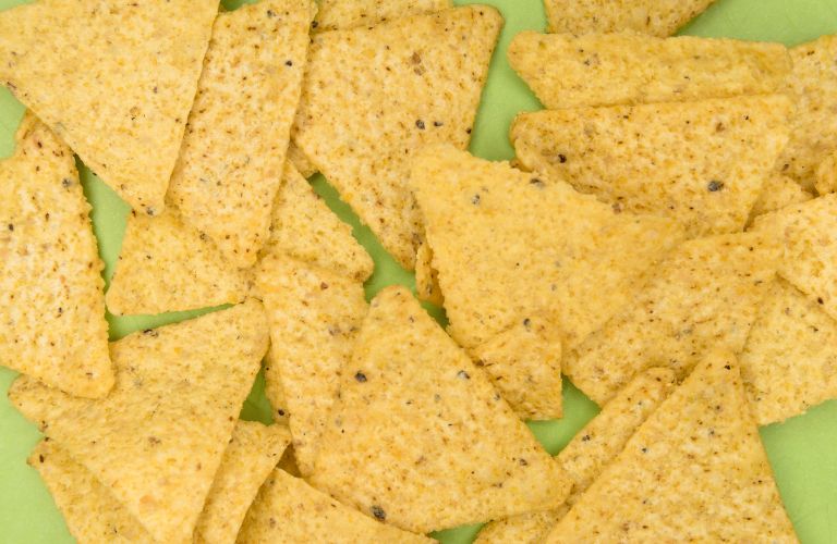 yellow corn tortilla chips in triangle shape resting on a green table