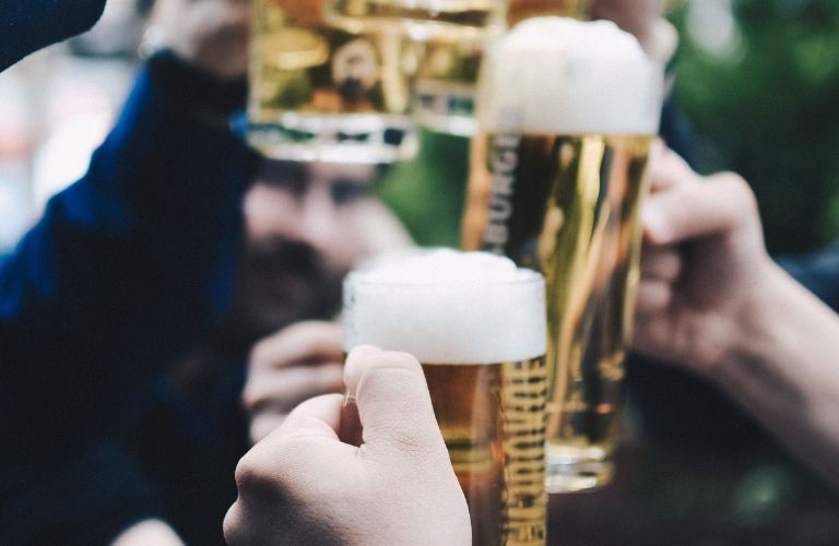 hands bringing mugs of frothy beer together in celebration of St. Patrick's day