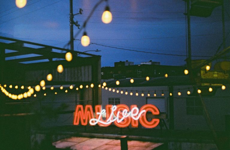 live music neon sign on patio with string lights and evening sky