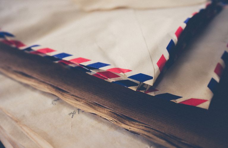 stack of worn paper envelopes from the postal service piled up on handwritten letters