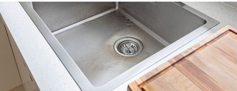 kitchen sink close up on drain with cutting board in view