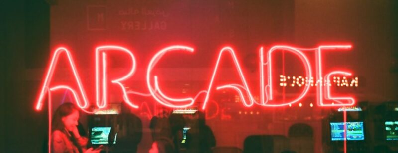 large red neon sign that reads arcade hung on a window