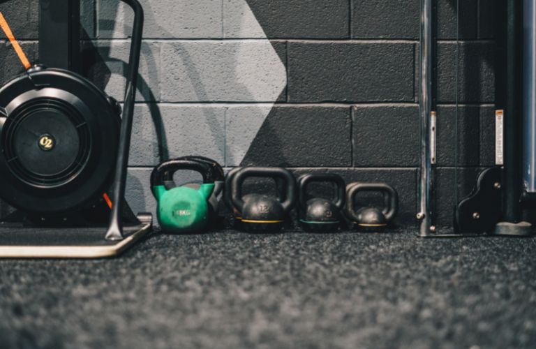 weights resting on the ground against a wall in a gym