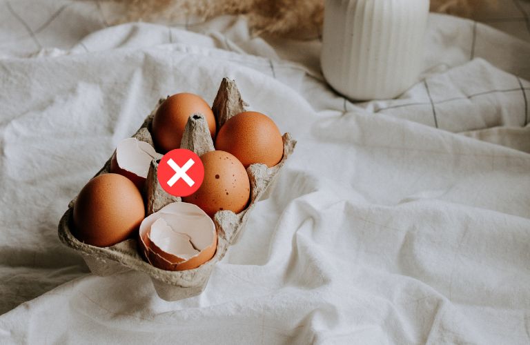 eggs and eggshells in an egg container on a white cloth