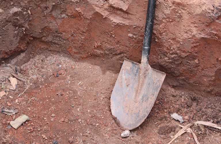 shovel sitting at the bottom of a dry hole in the ground