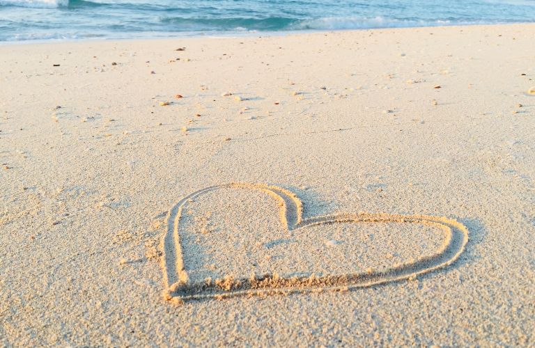 heart symbol drawn in clean sand at the beach