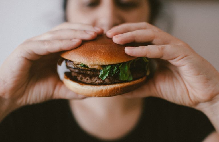 person holding a burger up to their face about to eat it