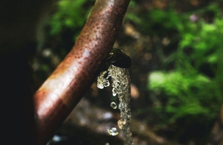 metal spout of a well with water coming out of it