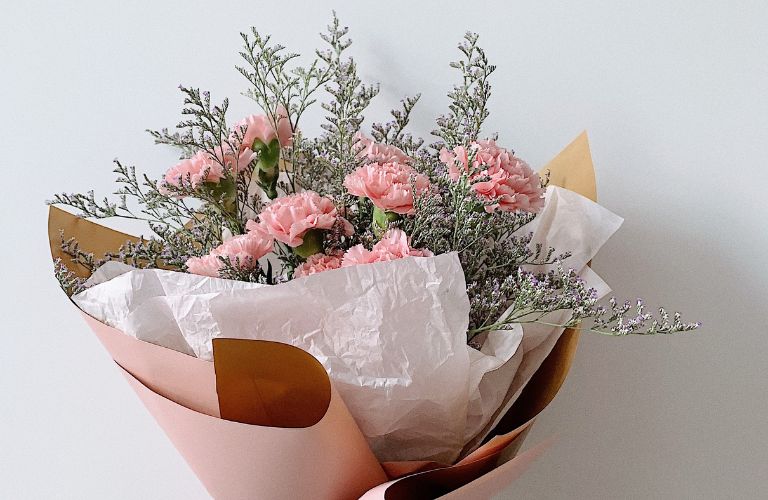 pink and white arrangement of flowers in brown paper