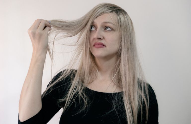 woman looking at her hair with concern