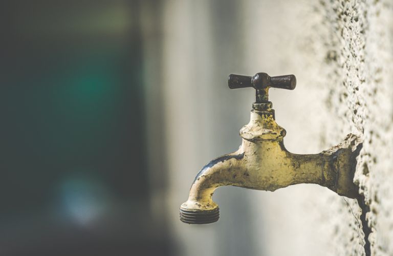 water spigot sticking out of a stucco wall