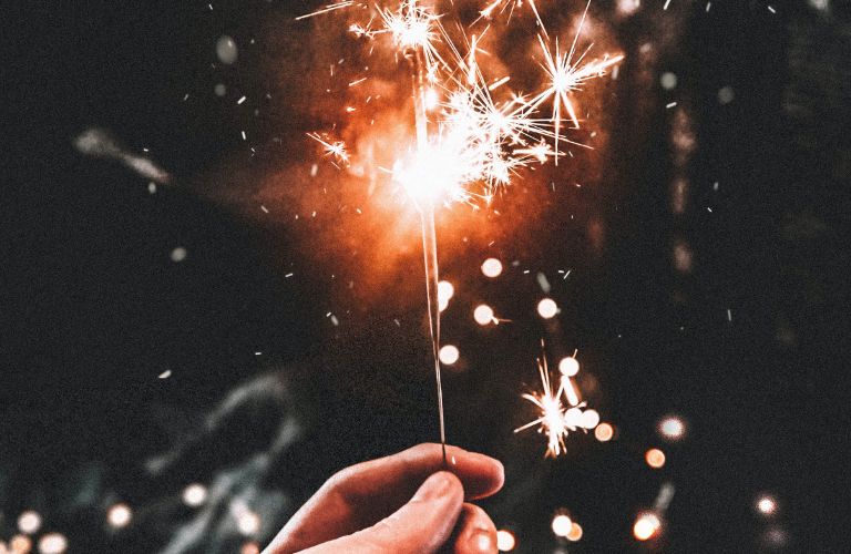 sparkler held in hand glowing bright orange and white