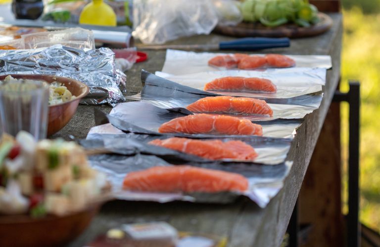 fillets of salmon on aluminum foil prepared for cooking on a grill