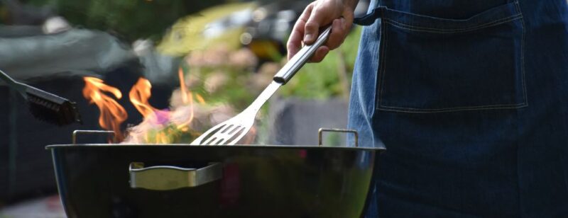 person grilling and holding a metal spatula