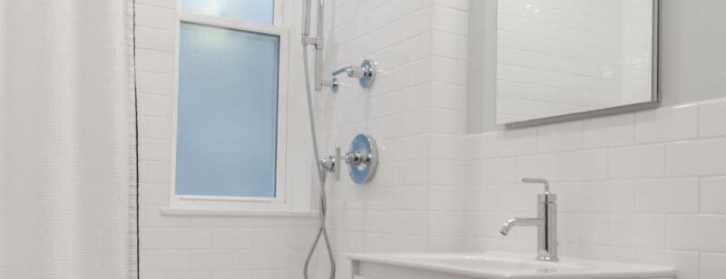clean white shower in a bathroom with a frosted glass window