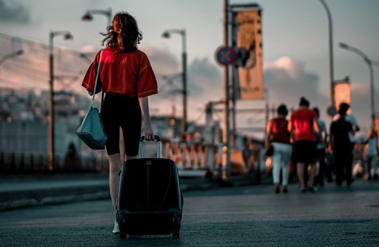 woman traveling in Europe with rolling luggage and purse