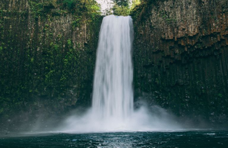 Tall waterfall with lots of white spray coming down cliffside