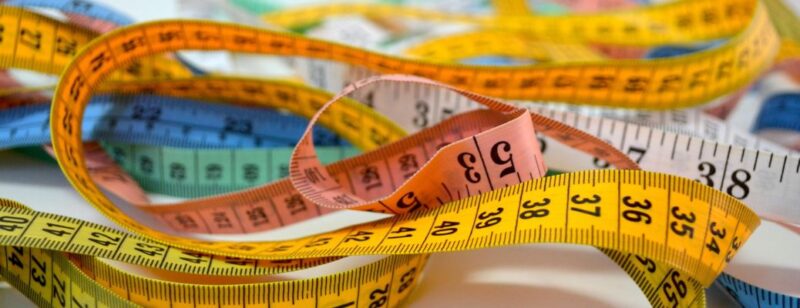 assorted colored tape measures strewn out on a white table