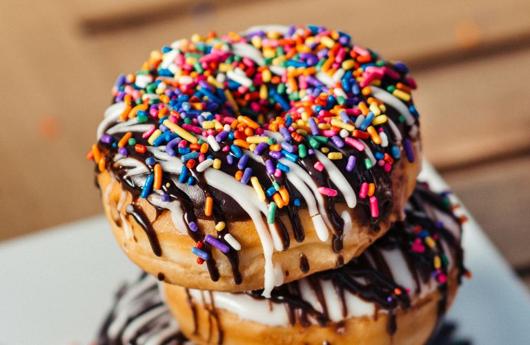 stack of frosted and sprinkled donuts with vibrant colors and chocolate