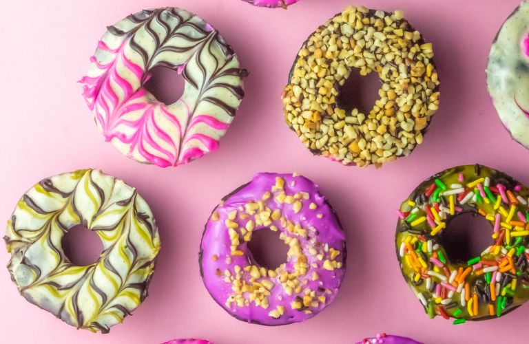 specialty donuts laid out on a pink table