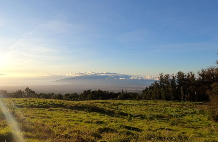 Volcanic mountain on Maui, Hawaii seen from a distance with clouds and grass