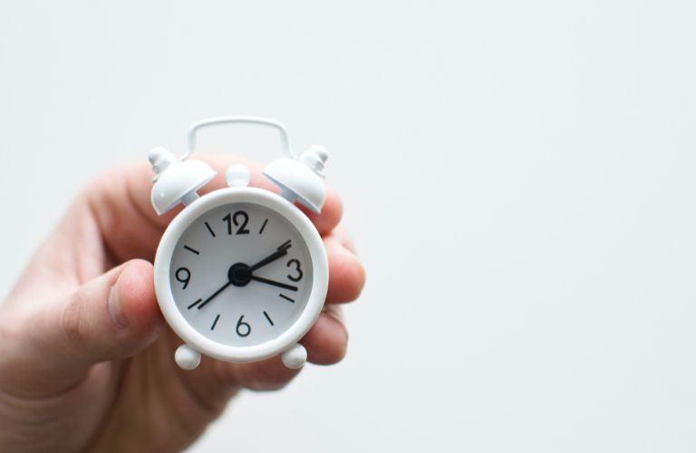 small analog alarm clock held in hand