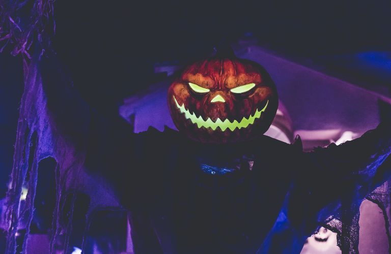 spooky jack o lantern head on torn cloth body in purple light