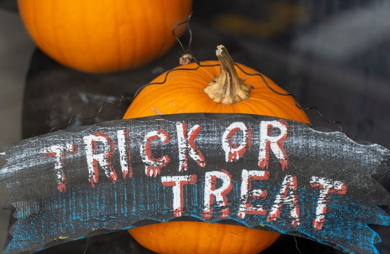 two pumpkins on a table with a wooden sign that says trick or treat on it