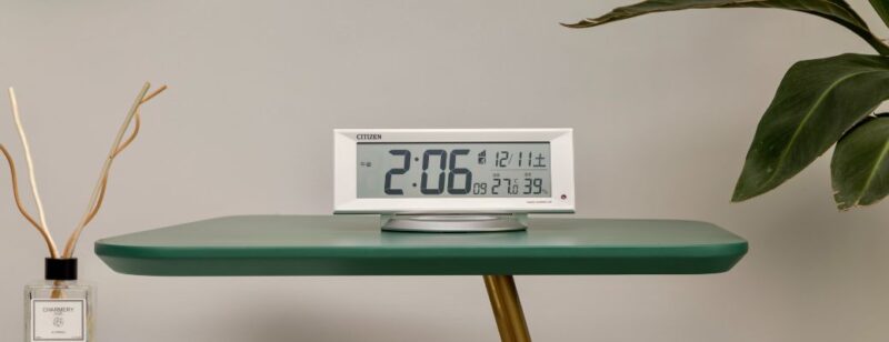 white digital clock sitting on a glass table in a modern room