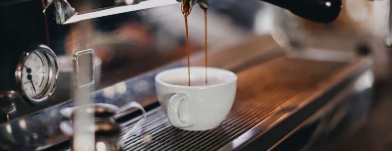 cup of espresso being poured in a coffee shop into a clean white mug