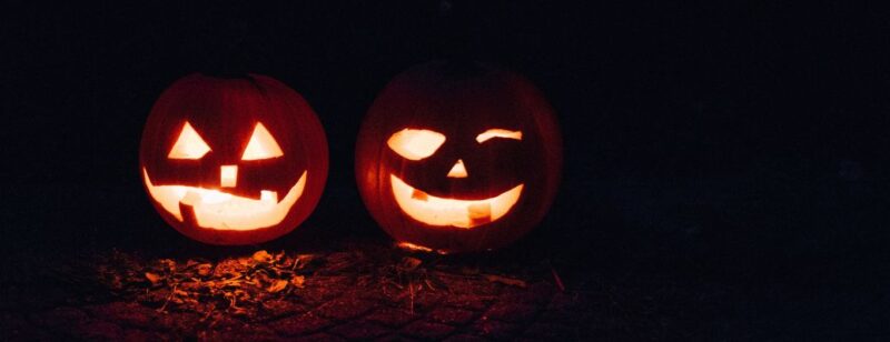 two lit jack o lanterns glowing in the night