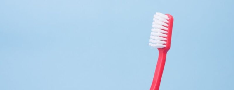 lone toothbrush leaning to the right against a light blue background