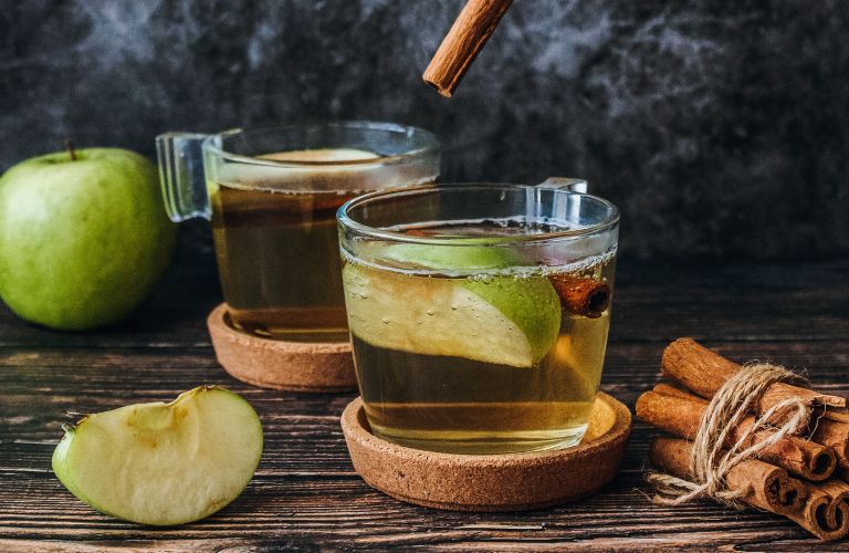 apple juice with slices of apple and cinnamon sticks