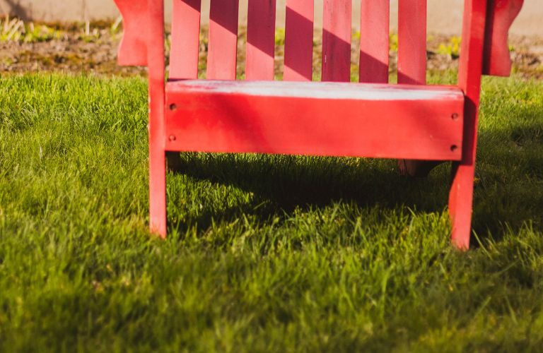 red lawn chair sitting on the grass outside a house