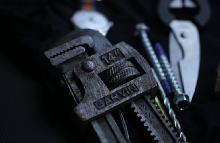 pipe wrench and other wrenches laid out on a tabletop