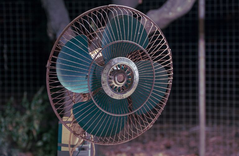 blue fan blades of a standing fan with cover on